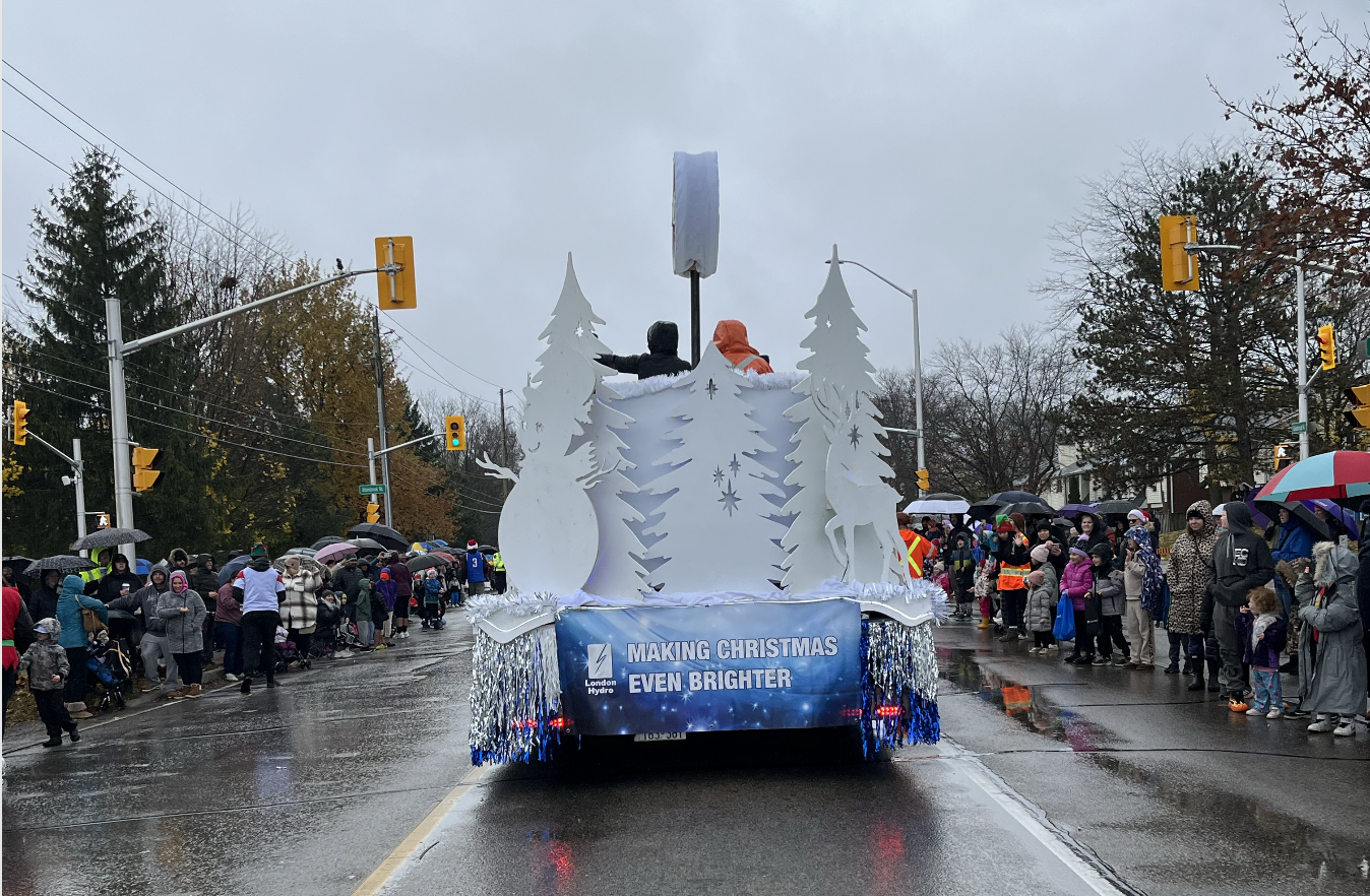 A parade float driving down the street with crowds on both side. 