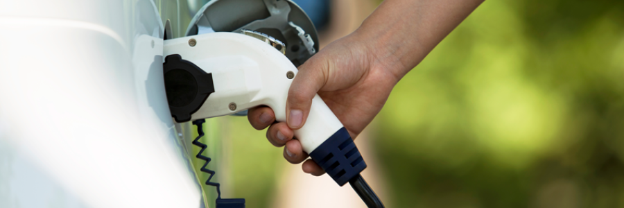 A hand plugging in an electric vehicle to charge