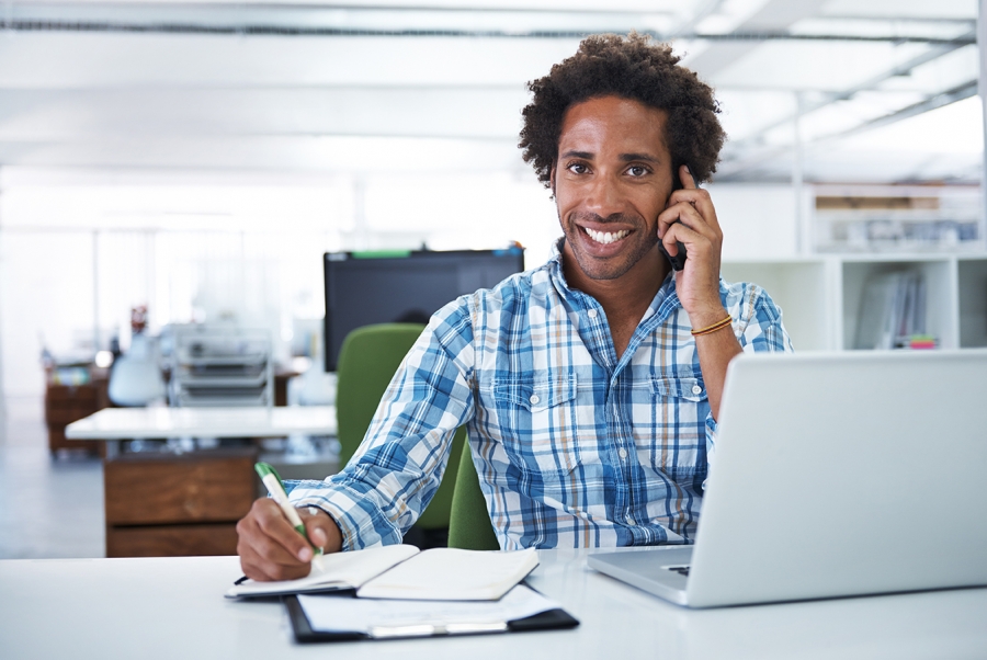 Working at the office Man sitting in front of laptop talking on the phone
