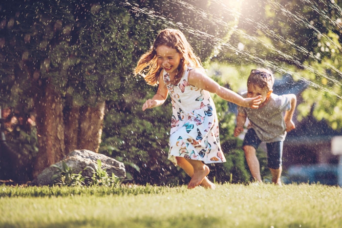 Photo of children running through the sprinkler