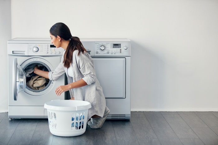 Photo of a person loading clothes into the washing machine
