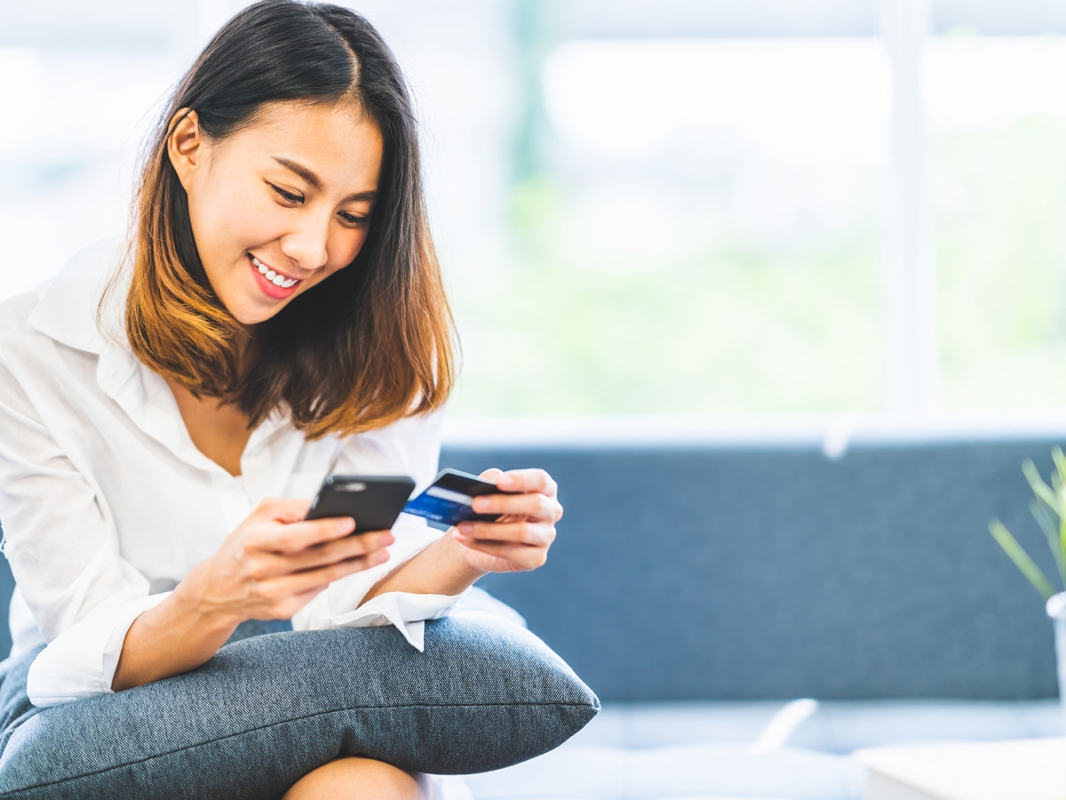 Pay with credit card Woman using her phone to pay online with her credit card