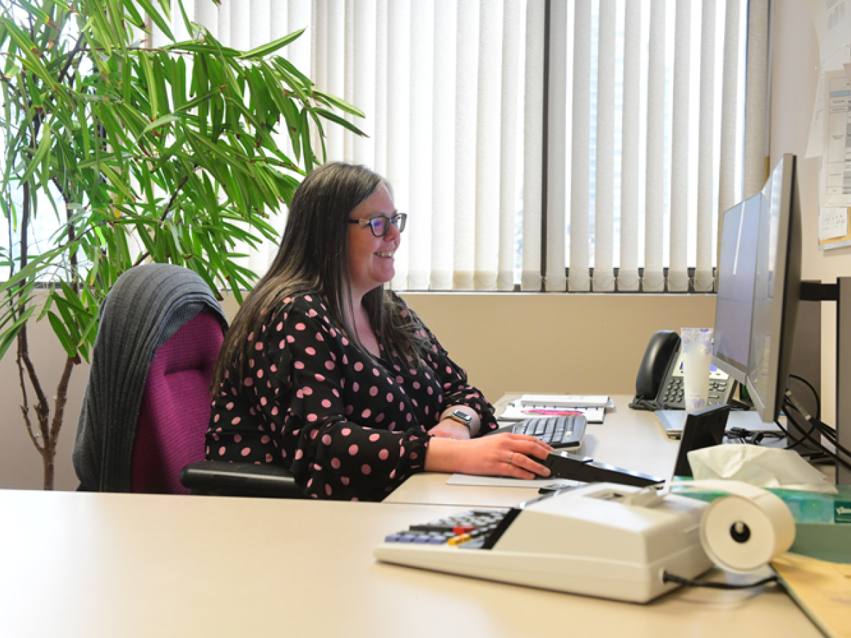 London Hydro Finance Employee Women sitting at a desk smiling while working on a computer