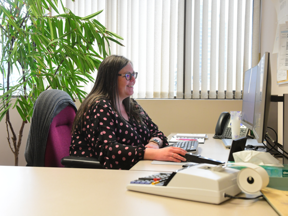 Women sitting at a desk smiling while working on a computer